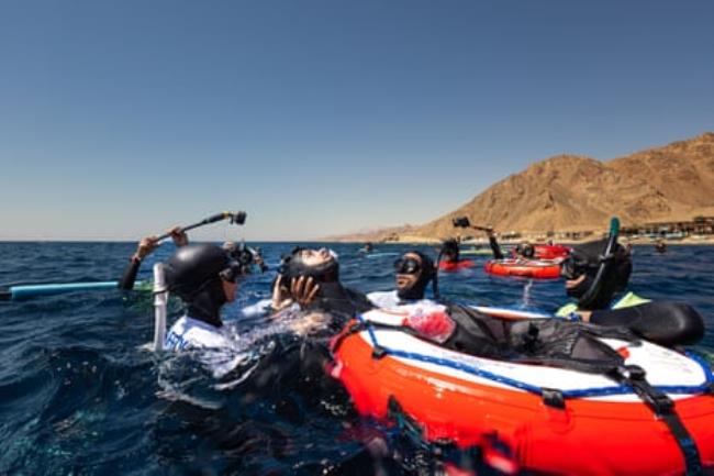 Divers gather around a life ring on the surface of the water